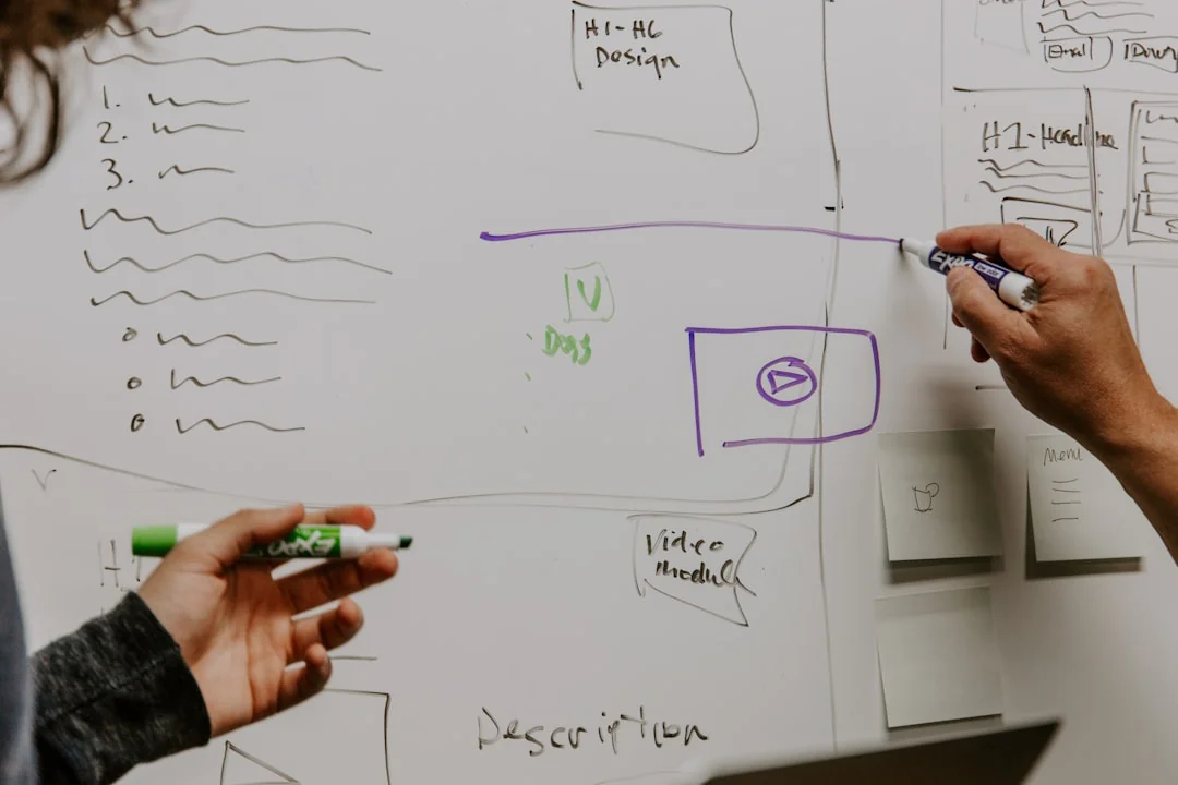 Two colleagues collaborate on a marketing strategy using a whiteboard, focusing on user-generated content.